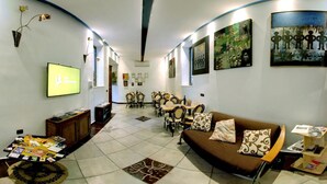 Ein modernes Wohnzimmer mit einem braunen Sofa, einem Couchtisch mit Zeitschriften, einem Fernseher und einem Essbereich mit Stühlen und einem Tisch.