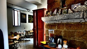 Ein Essbereich mit Kamin aus Ziegelsteinen, einer Kaffeemaschine und einem reichhaltigen Frühstücksbuffet auf der Arbeitsfläche.