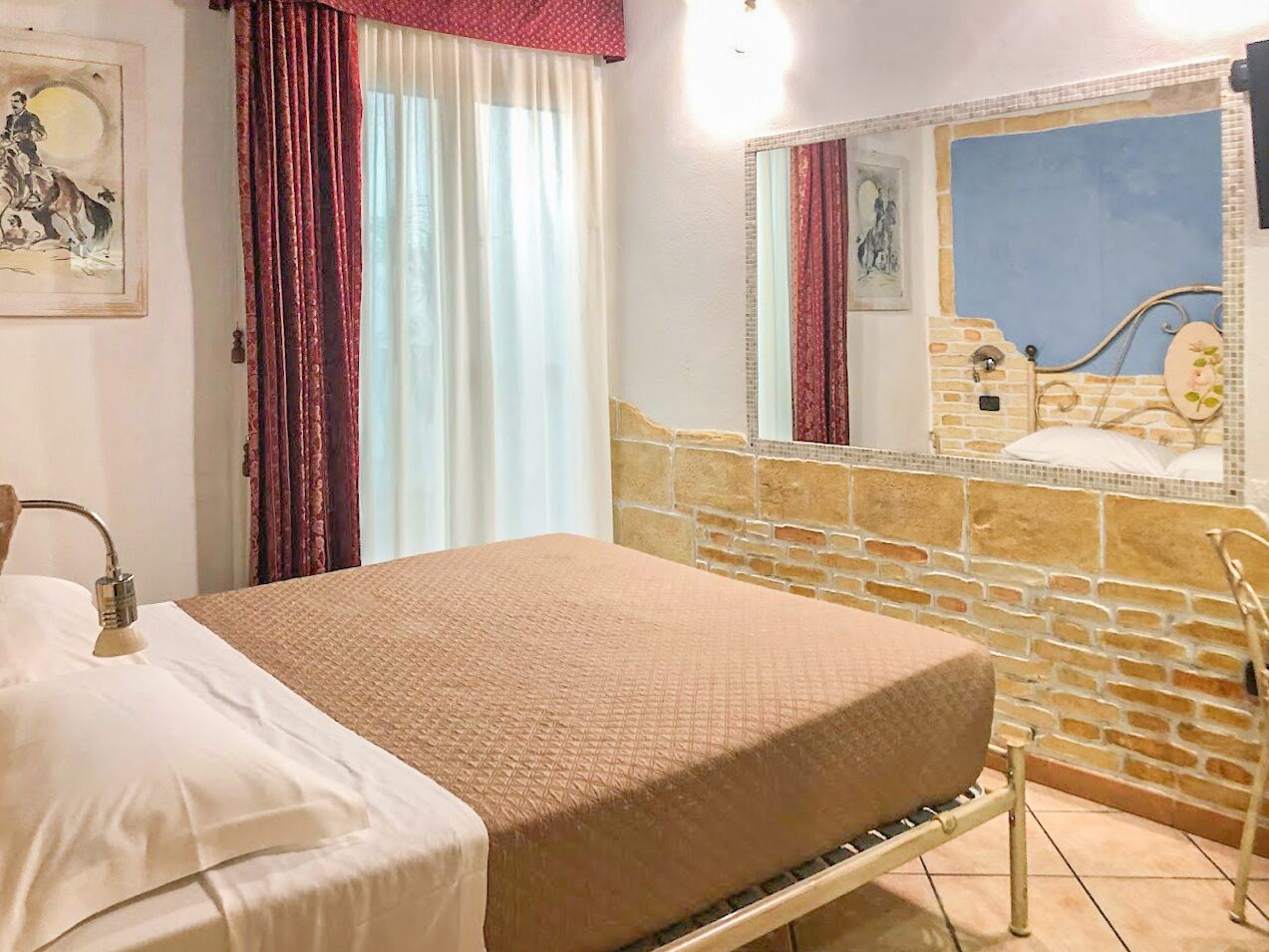 Una cama con cubierta color beige, una ducha con pared de piedra y una ventana con vistas a un cielo azul.