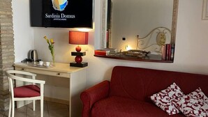 A modern living room with a TV, a desk, a red sofa, and a mirror. - Sardinia Domus (Cagliari)