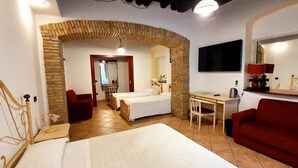 A hotel room with a bed, a desk, a red sofa, and a TV. - Sardinia Domus (Cagliari)