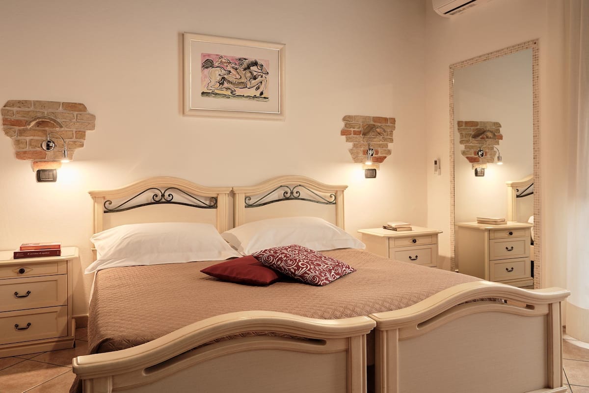 A bedroom with a bed, nightstands, a dresser, and a large mirror.