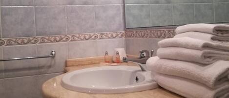 Un baño con lavamanos, espejo y toallero.