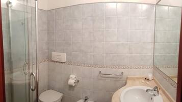 Une salle de bain avec une douche à parois de verre, des toilettes, un bidet et deux lavabos.