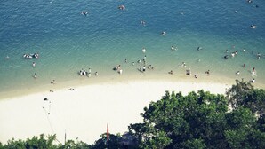 Een strand met helder water en mensen die zwemmen en zonnebaden.