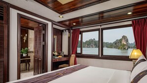 Hotelkamer met een bed, een bureau met lamp, uitzicht op een wateroppervlak en een raam met gordijnen.