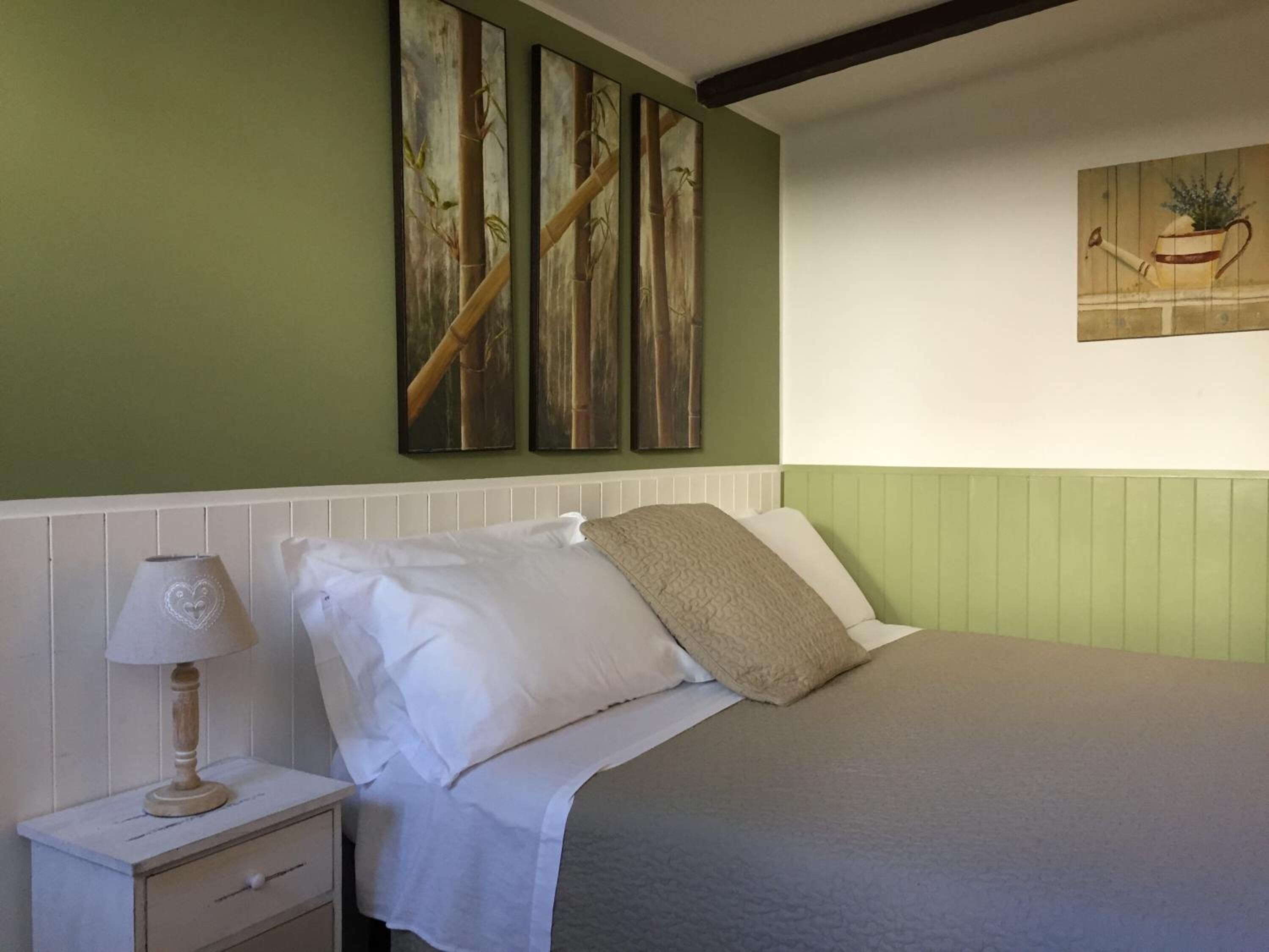 Ein Schlafzimmer mit Bett, Nachttisch, Lampe und Wandbildern.