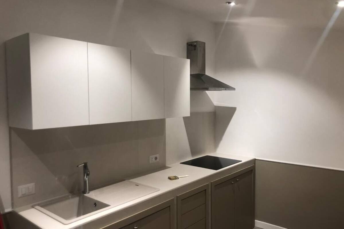A modern kitchen with white cabinets, a black stove, and a sink.