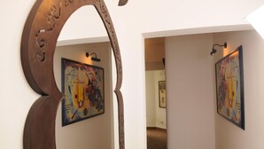A hallway with abstract paintings on the walls and a decorative metal archway. - Possidonea 28 Bed & Breakfast (Reggio Calabria)