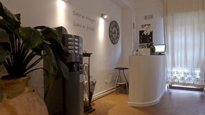 A modern hotel lobby with a coffee machine, a clock, and a reception desk. - Possidonea 28 Bed & Breakfast (Reggio Calabria)