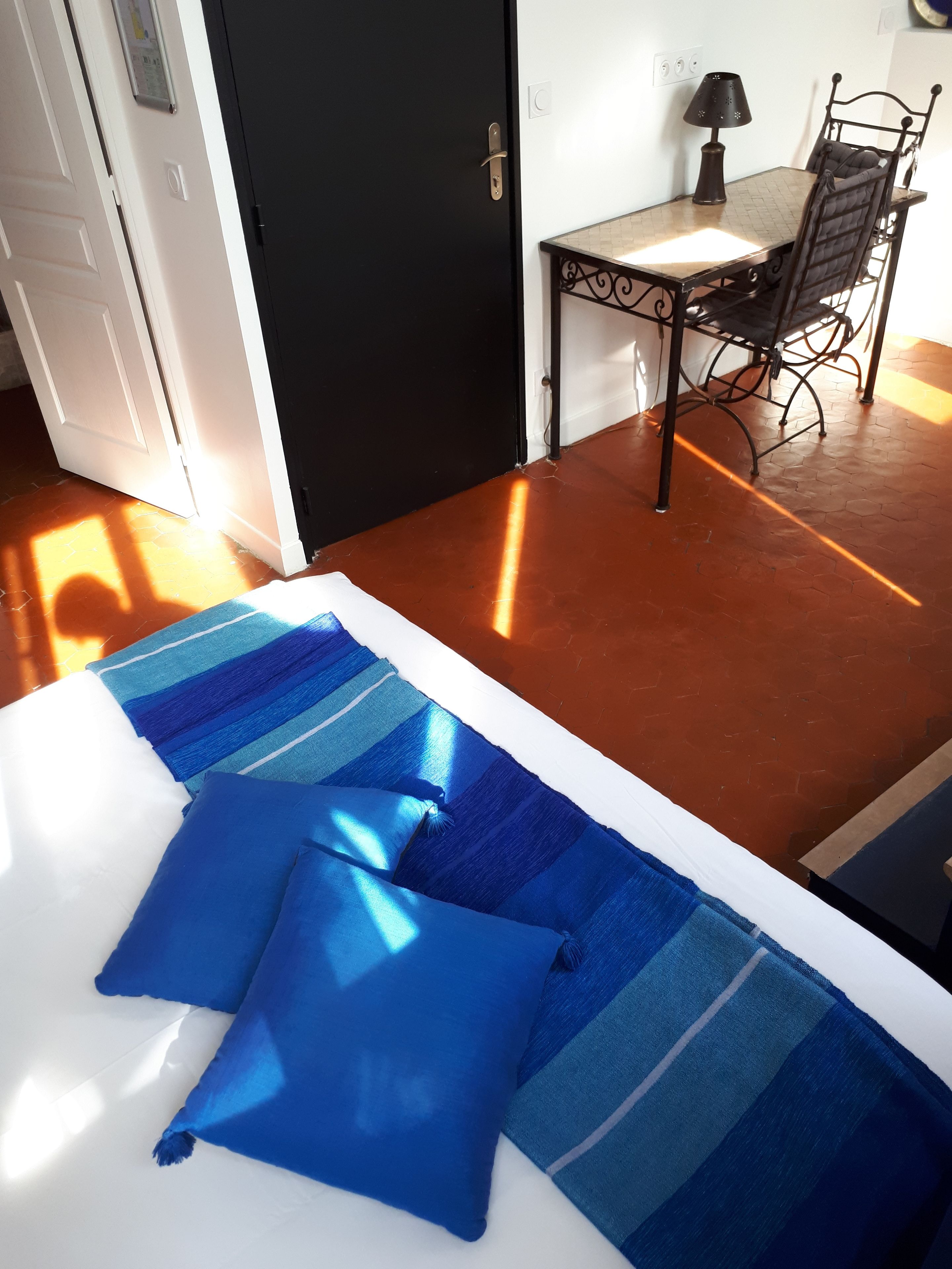 Una habitació amb llit, taula i cadira, i una porta.
