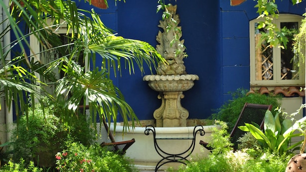 A courtyard with a fountain, benches, and lush greenery. - Le Ryad Boutique Hôtel (Marseille)