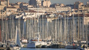 A marina with numerous sailboats docked, surrounded by a densely packed urban area with historic buildings. - Le Ryad Boutique Hôtel (Marseille)