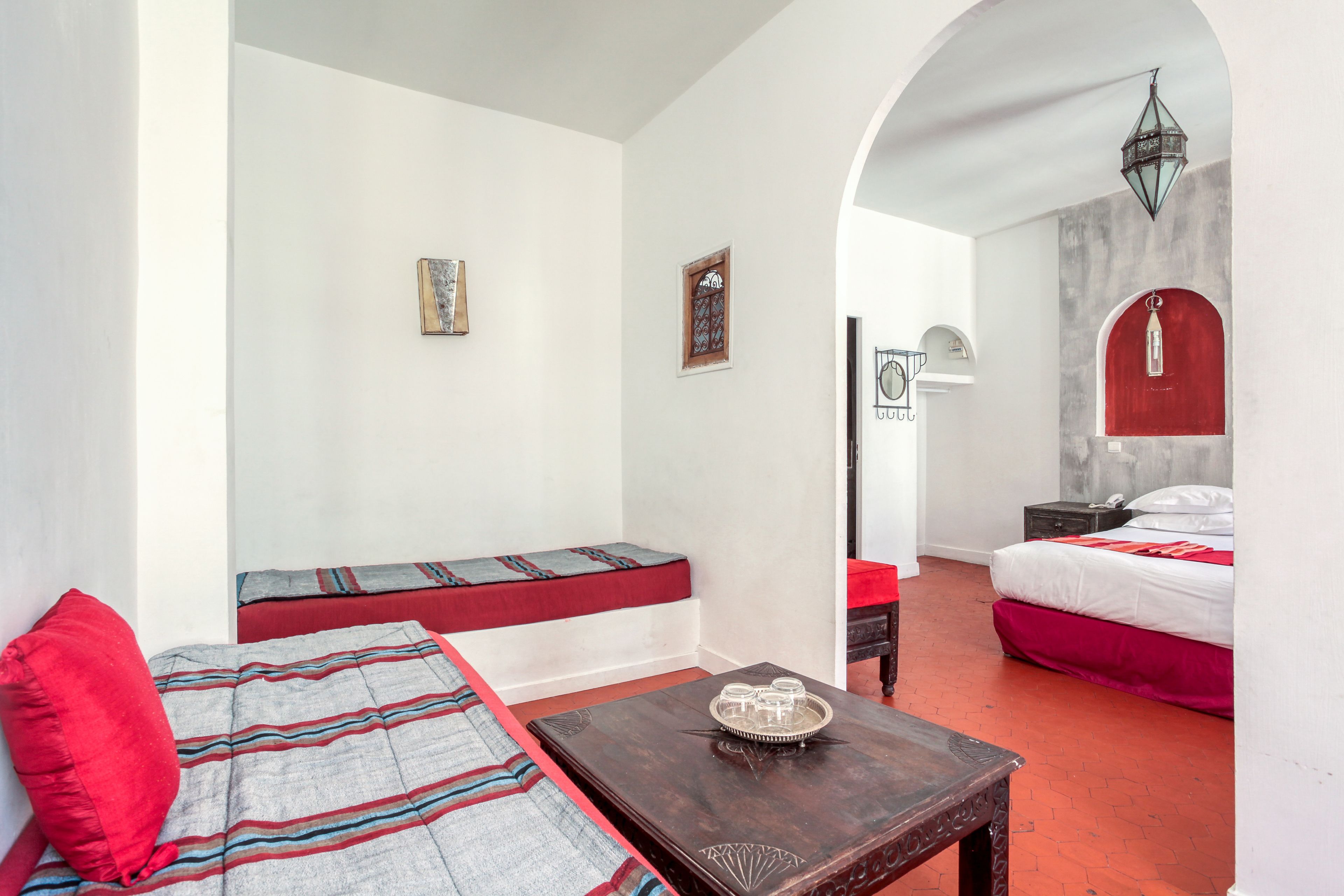Une chambre d’hôtel avec un lit, un banc, une table et une porte donnant sur une autre pièce.
