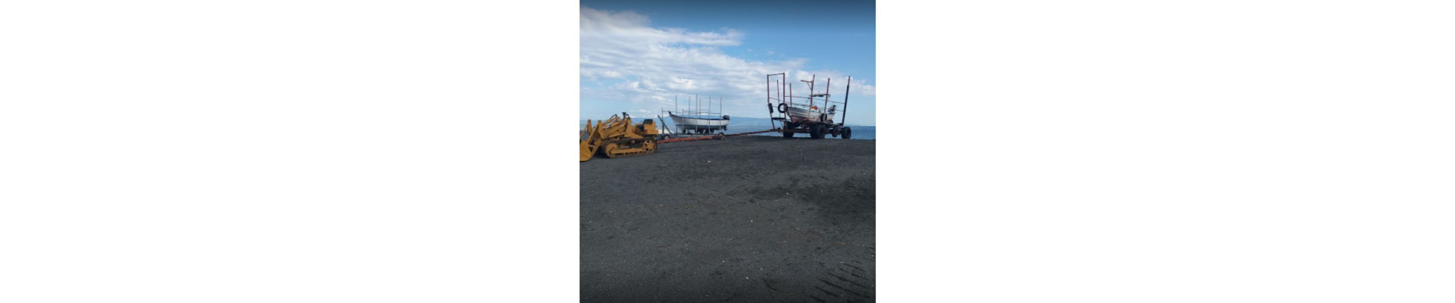 Ein Strand mit einem großen, gelben Fahrzeug und einem Boot im Sand.