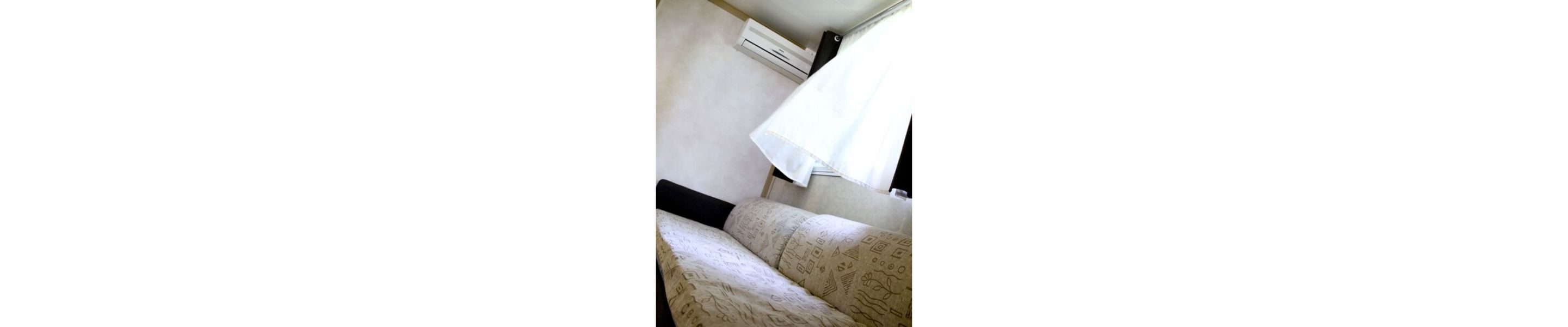 A room with a bed, a white curtain, and a patterned carpet.