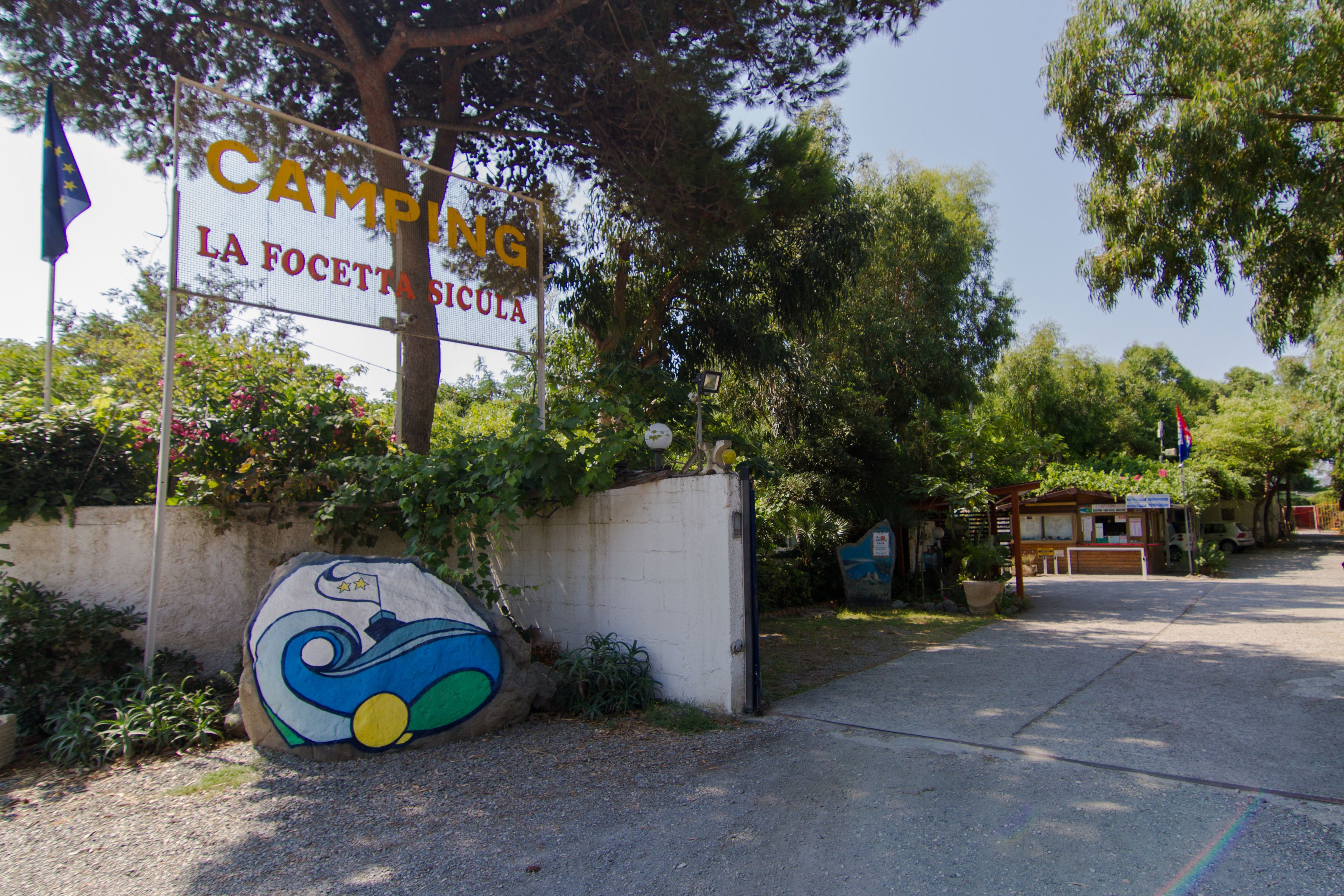 A sign for "Campion La Focetta Sicula" with a colorful mural on a wall.
