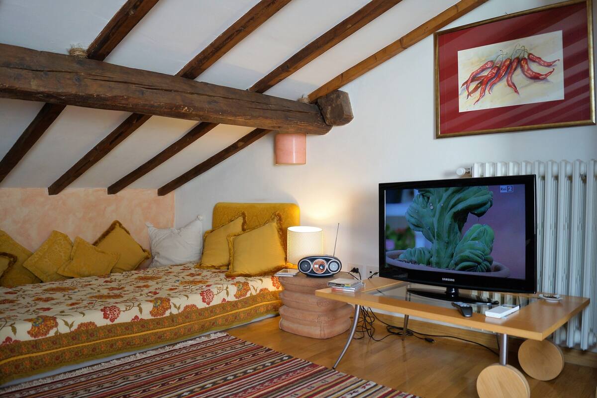 A cozy bedroom with a bed, a television, and a lamp.