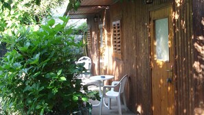 A wooden cabin with a covered patio, a table, and two chairs.