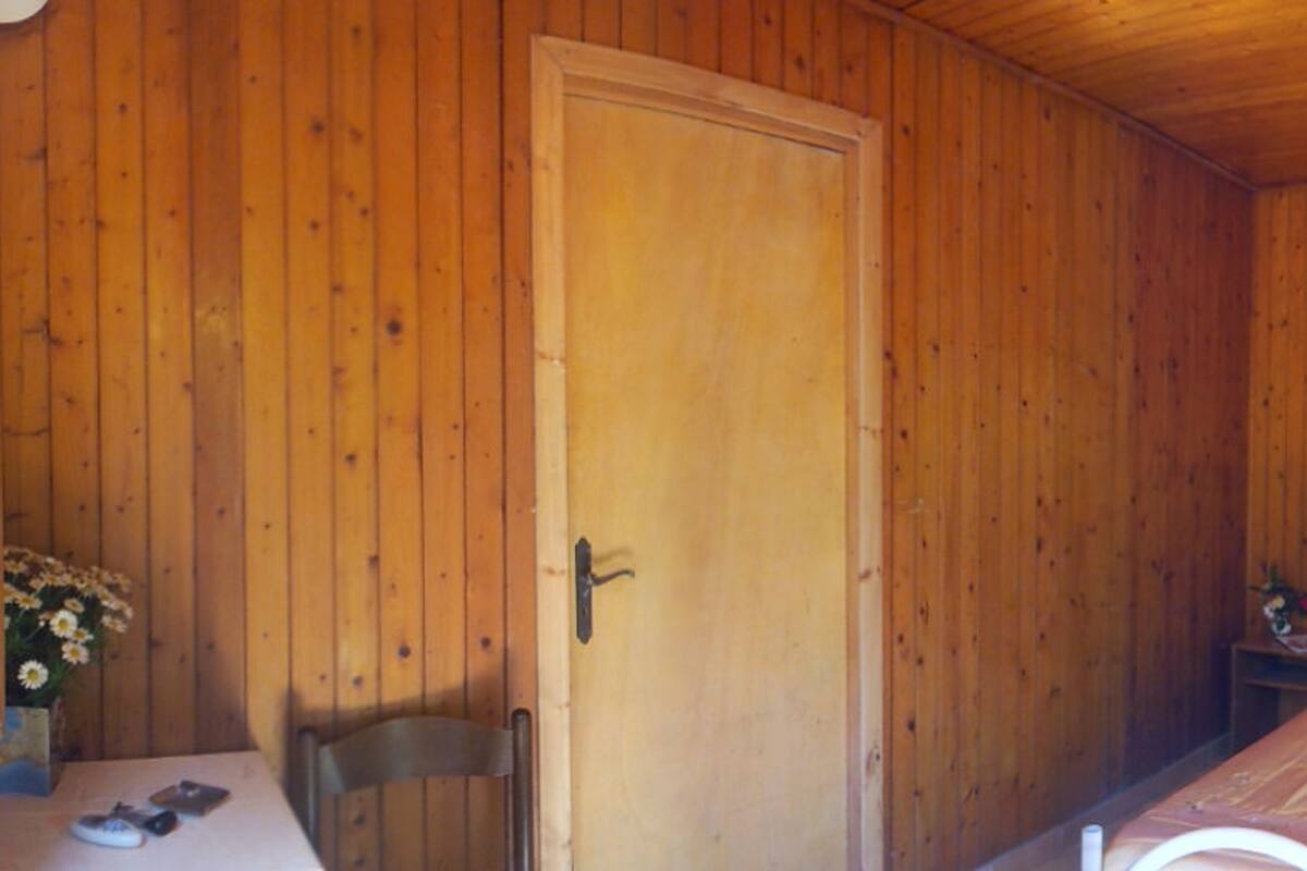 Une pièce aux murs lambrissés, contenant un lit, un bureau et une chaise.