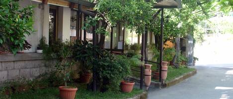 A building with a covered porch, potted plants, and a clear sidewalk.