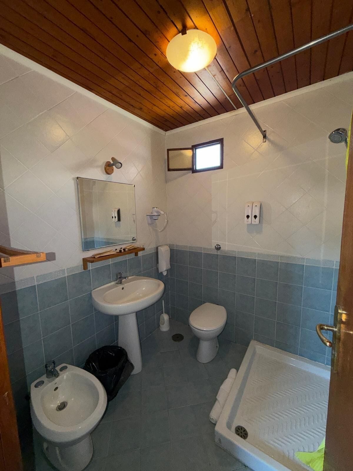 Une salle de bain avec un plafond en bois, un lavabo, des toilettes, un bidet et une douche.