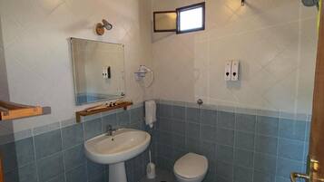 Une salle de bain avec un plafond en bois, un lavabo, des toilettes, un bidet et une douche.