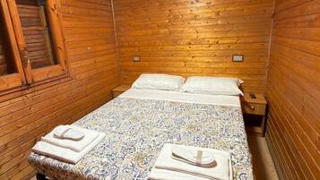 Una stanza con rivestimenti in legno, un letto, una finestra e un condizionatore.