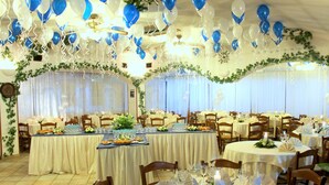 A banquet hall with round tables set for dining, featuring white tablecloths and glassware.