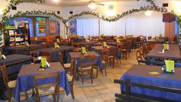 A restaurant with multiple tables and chairs, some with menus on them.