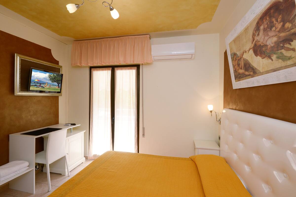 A bedroom with a bed, a desk, and a television.