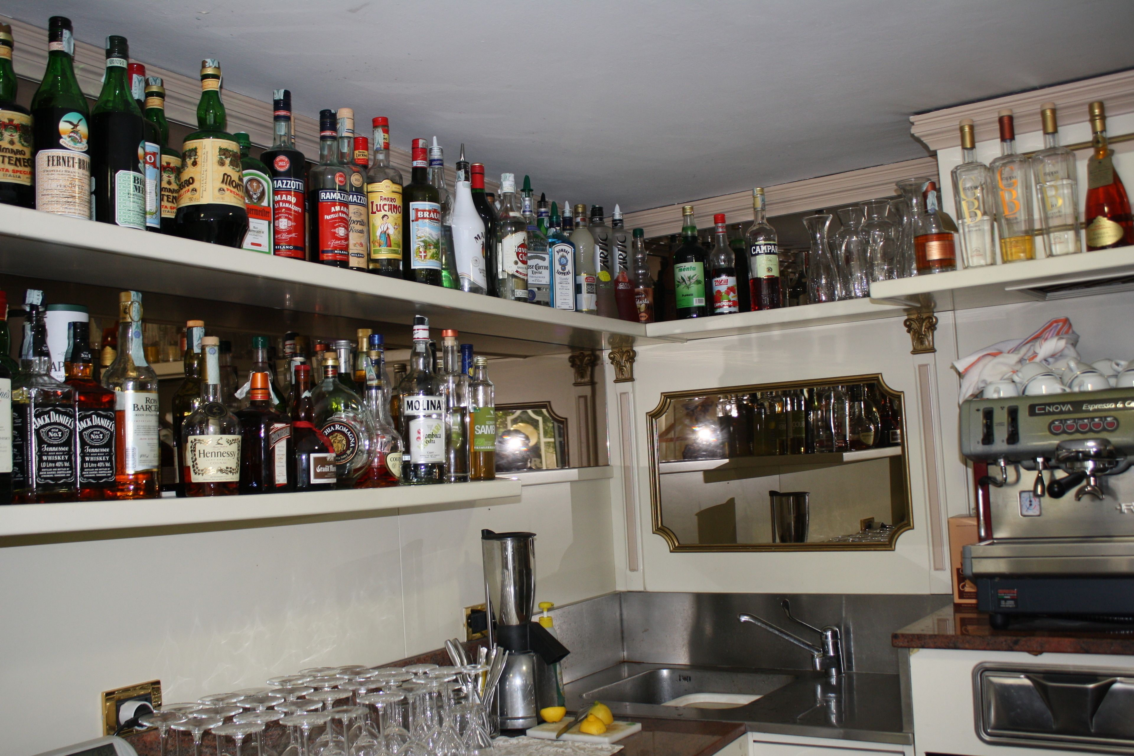 Zona de bar con estantes llenos de botellas de licor y vasos.