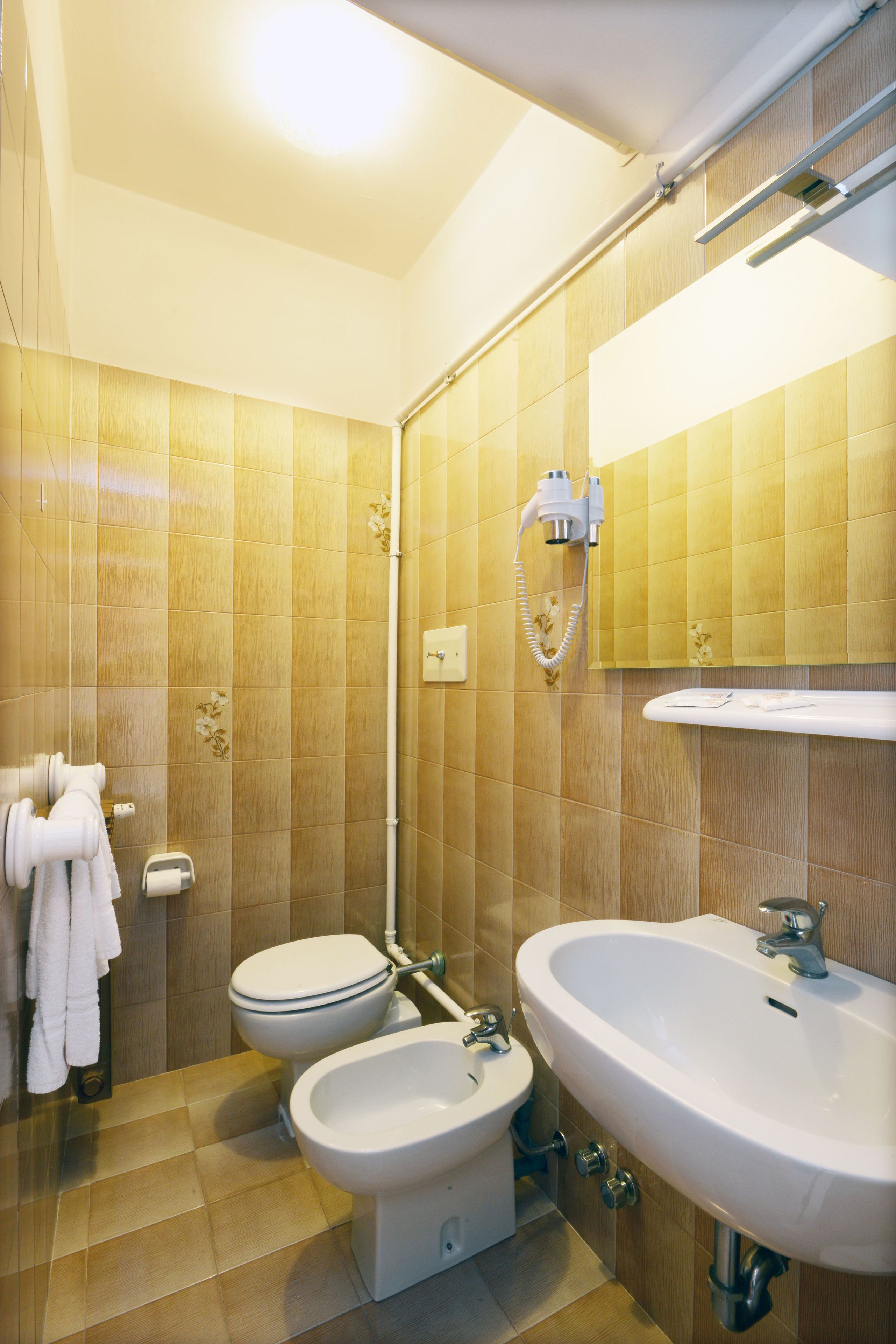 Un baño con inodoro, bidé, lavabo y toallero.