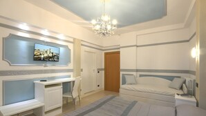A bedroom with a bed, bedside table, nightstand, and a television mounted on the wall. - Hotel Ristorante Commercio (Salò)