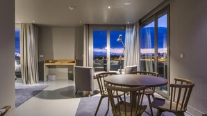 A modern hotel room with a dining area, a desk, and a large window with a city view. - Villa C Boutique Hotel (Vila do Conde)