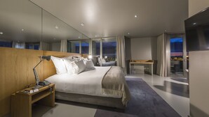 A modern hotel room with a large bed, bedside table, lamp, and a TV. - Villa C Boutique Hotel (Vila do Conde)