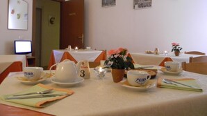 Un espace repas avec des tables mises pour le service, comprenant des tasses et des assiettes ornées du logo « PEZZA ».