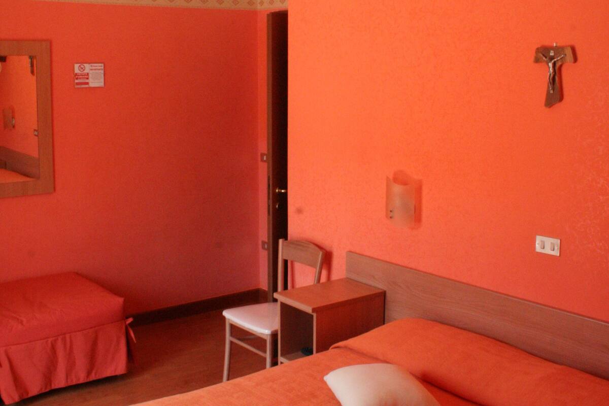 A room with two beds, a chair, and a small table.