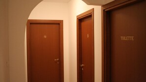 Un couloir avec deux portes en bois, l’une portant l’inscription « 4 » et l’autre « TOILETTES ».