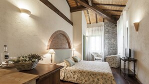 A bedroom with a bed, a desk with a lamp, a chair, and a television. - Tenuta Uccellina (Magliano in Toscana)