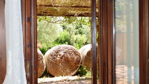 A doorway leading to a garden with hay bales and greenery. - Tenuta Uccellina (Magliano in Toscana)