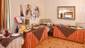 A buffet setup with various food items and beverages, a mirror, and abstract wall art. - Hotel Principe (Sanremo)