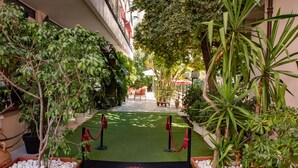 A hotel entrance with a red carpet leading to a reception area, surrounded by potted plants and a pathway. - Hotel Principe (Sanremo)
