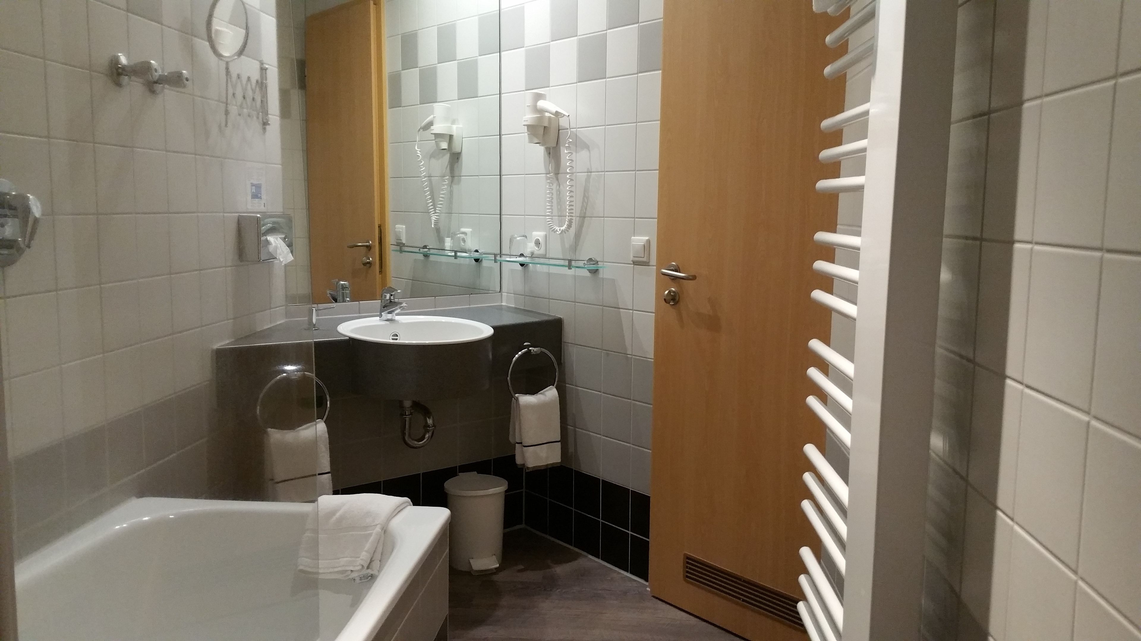 Un baño moderno con bañera, lavabo, espejo y secador de pelo.