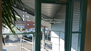 Vista a través de una ventana con un cartel que indica una zona para fumadores Raucher-Terrasse.