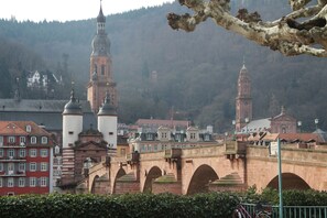 A historic bridge with arches, a prominent tower, and buildings with red and white facades. - Hotel Ifen (Wiesloch)