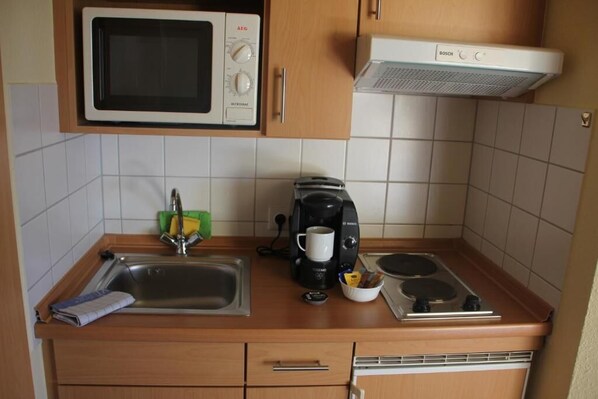 Una cocina compacta equipada con microondas, tostadora, cafetera y estufa.
