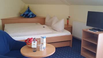 Een hotelkamer met een bed, een televisie, een klein tafeltje met snacks en een blauwe stoel.