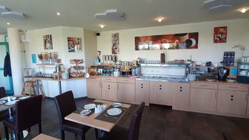 A restaurant with a counter, seating area, and various food and drink items.