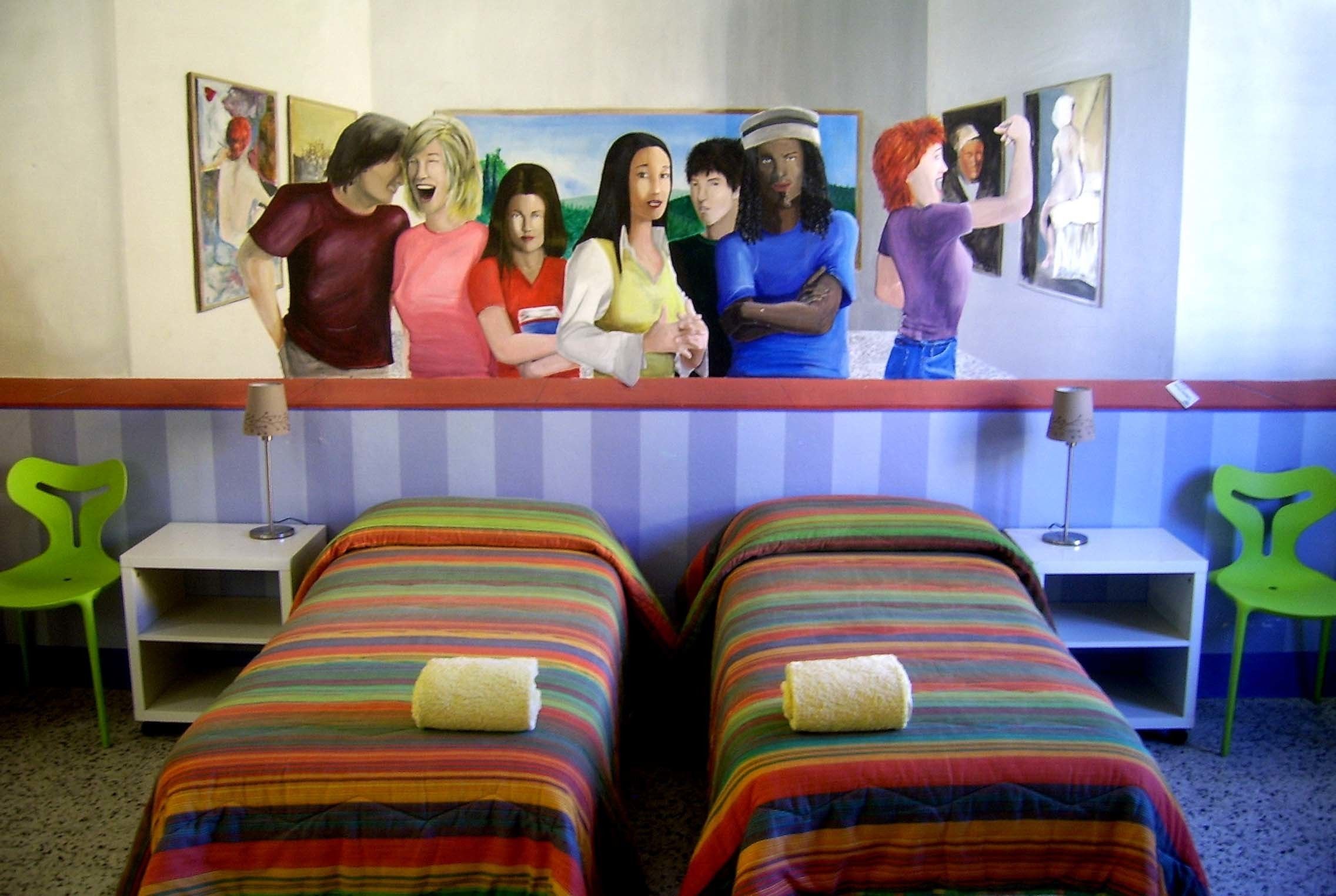 A hotel room with two beds, a painting on the wall, and a green chair.